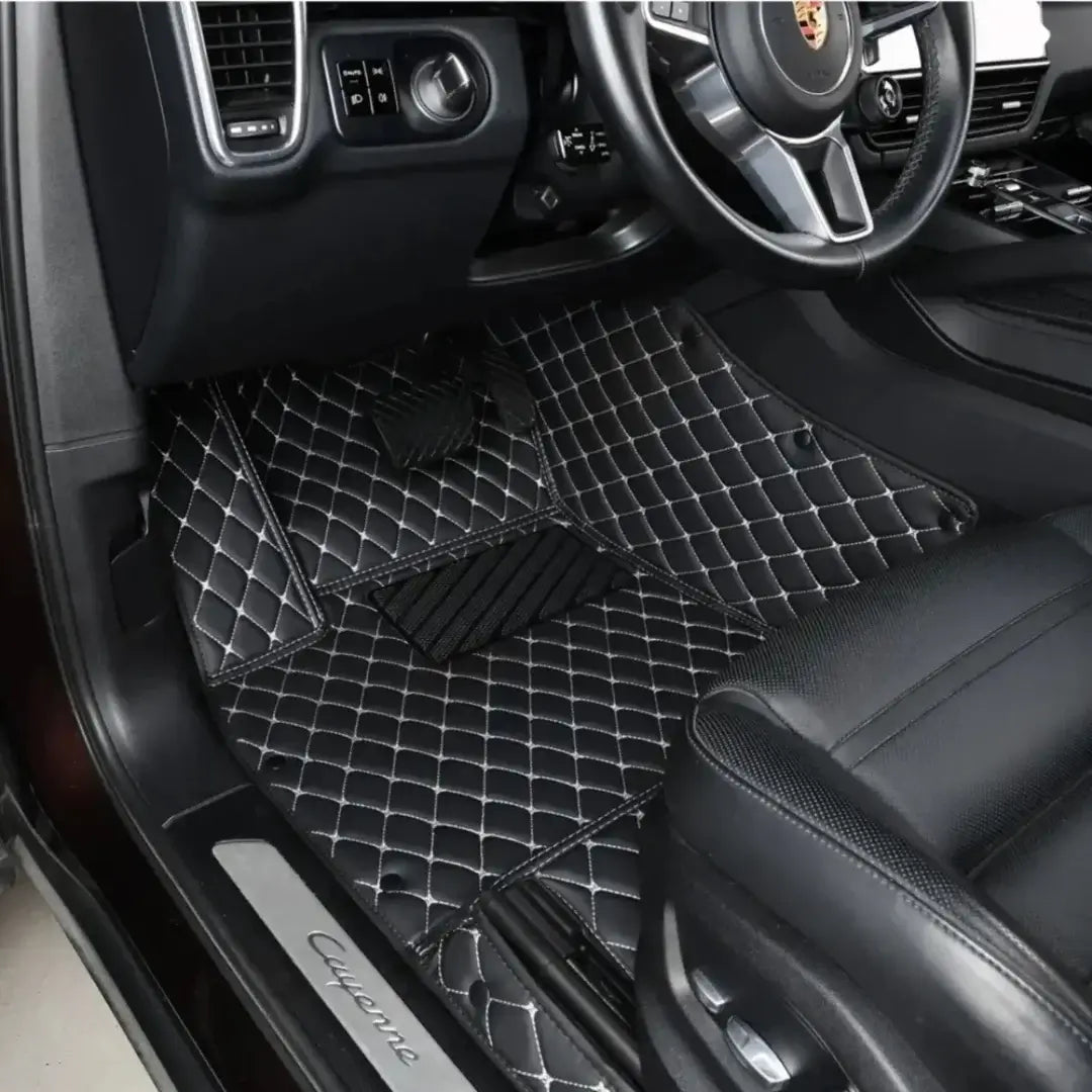 Car interior with black diamond-patterned floor mats on a Porsche Cayenne.