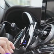 Wireless car charger closing its arms around a phone and charging it